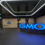 Insegna luminosa blu con il logo GMO all'ingresso degli uffici del gruppo nel palazzo Shibuya Fukuras a Tokyo