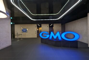 Insegna luminosa blu con il logo GMO all'ingresso degli uffici del gruppo nel palazzo Shibuya Fukuras a Tokyo