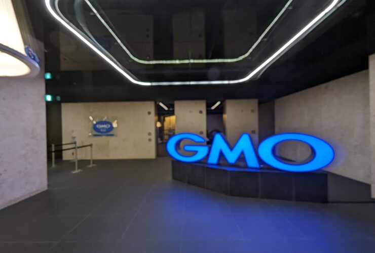 Insegna luminosa blu con il logo GMO all'ingresso degli uffici del gruppo nel palazzo Shibuya Fukuras a Tokyo