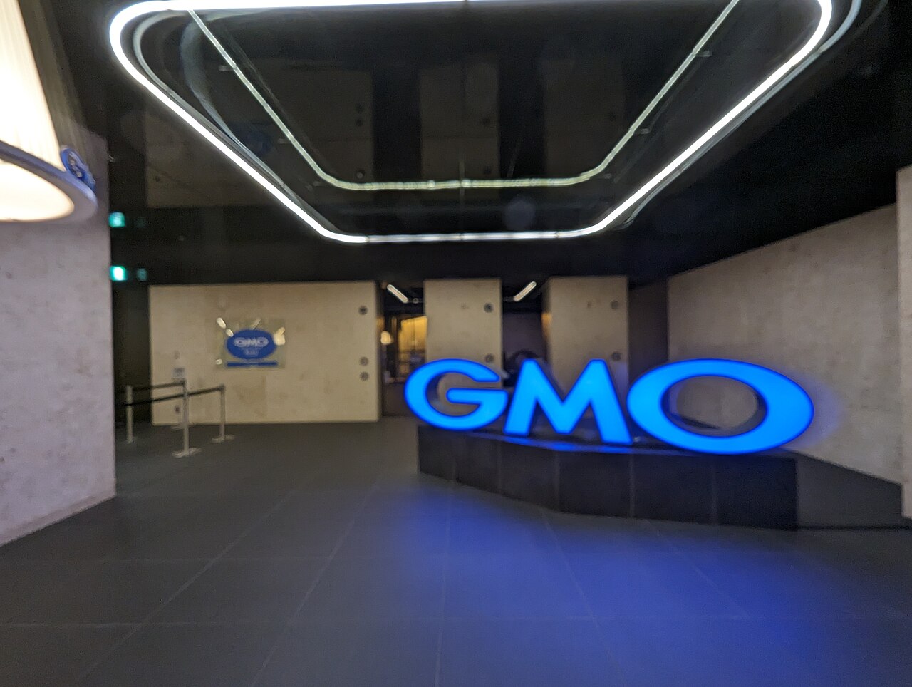 Insegna luminosa blu con il logo GMO all'ingresso degli uffici del gruppo nel palazzo Shibuya Fukuras a Tokyo